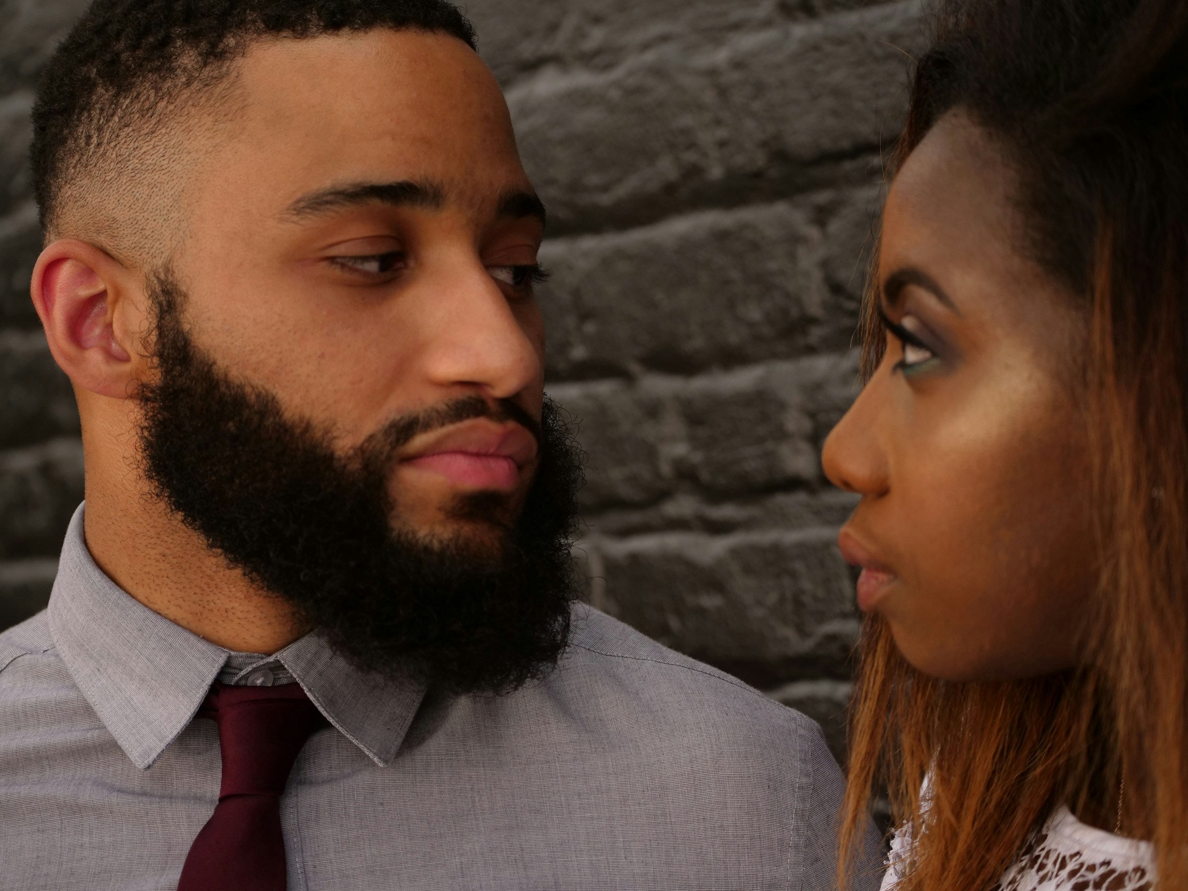 A somber close up of a couple looking at each other.